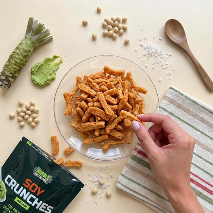 Wasabi Soy Crunches laid out surrounded by fresh ingredients for Wasabi, showcasing it as a plant-based soy protein snack from Nibble Network