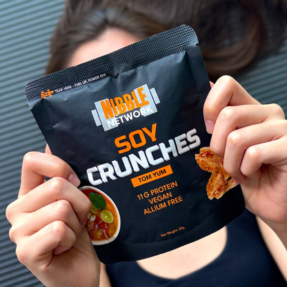 Gwen holding a package of Tom Yum Nibble Network Soy Crunches as a post-workout snack