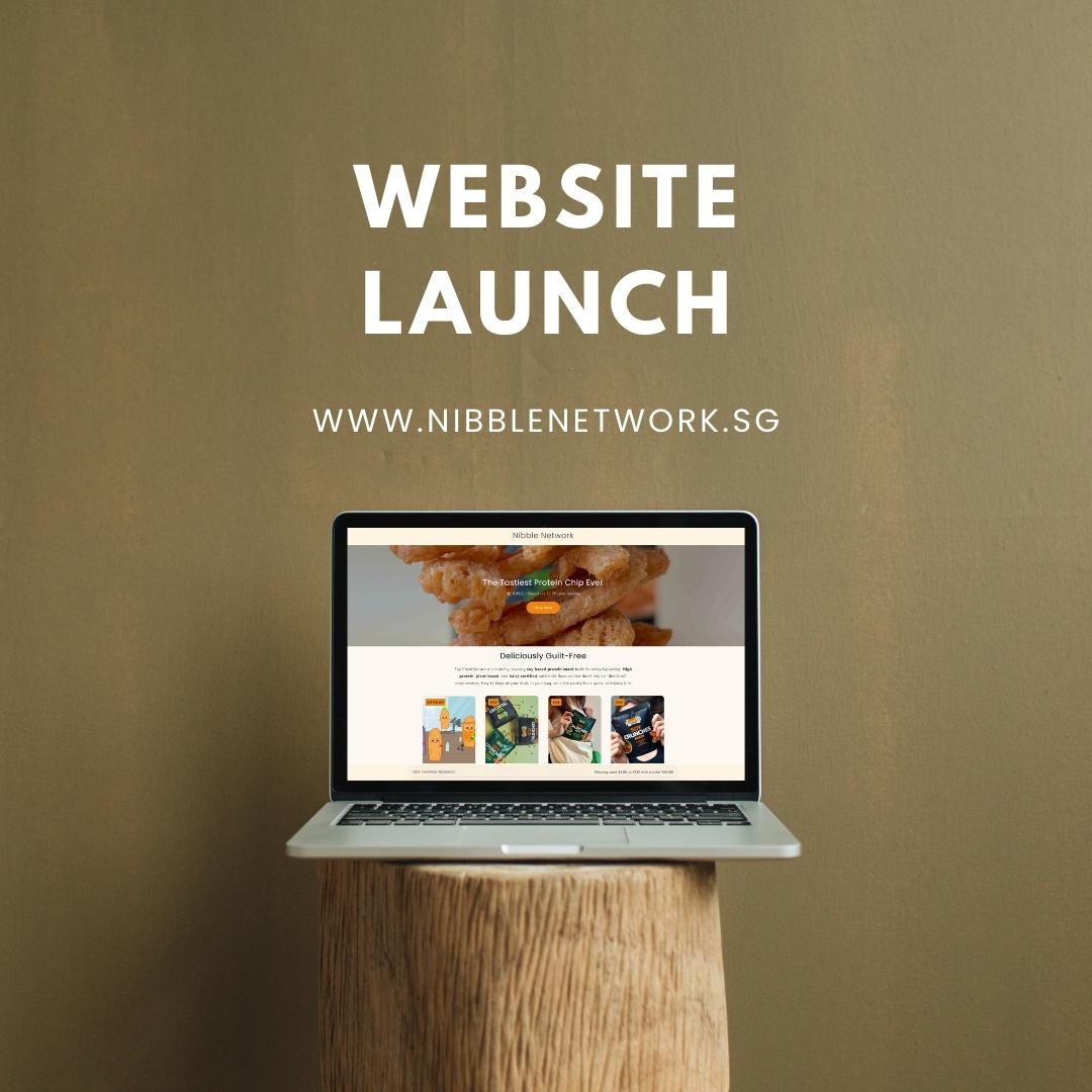 Laptop displaying the nibble network official website on a wooden stand with a brown background and text for a website launch.