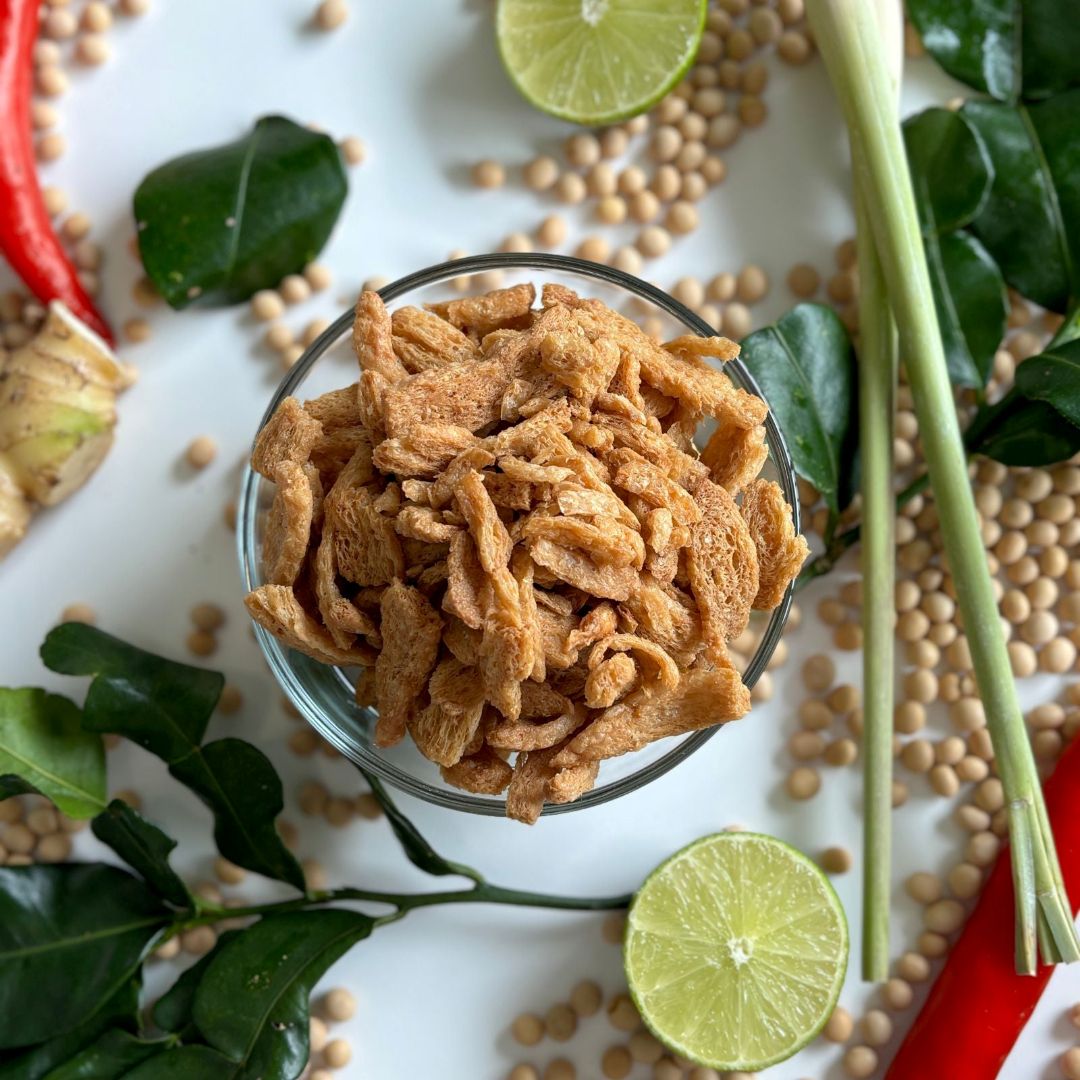 Tom Yum Soy Crunches laid out surrounded by fresh ingredients for Tom Yum, showcasing it as a plant-based soy protein snack from Nibble Network