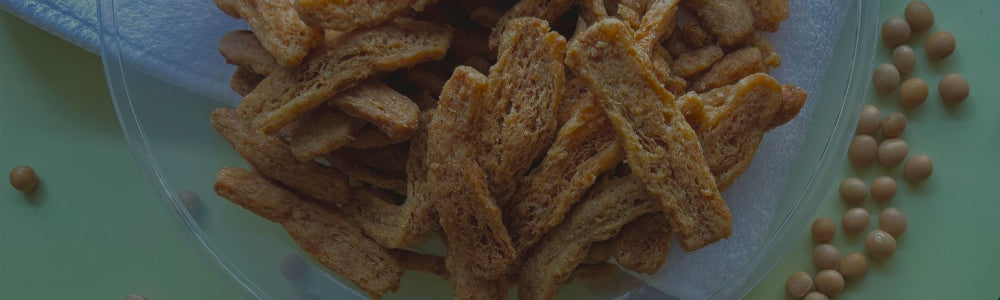 Soy Crunches on a transparent plate with scattered beans on a green surface